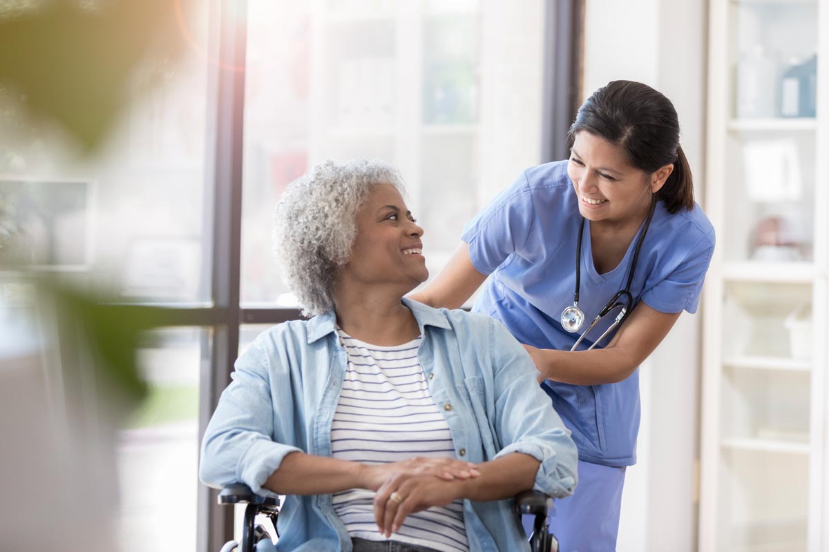 elderly woman in a wheelchair being attended to by a kind nurse